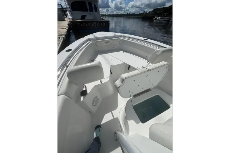 Slide: The Image of 2020 Sea Hunt Triton 210 boat interior with seating and storage, docked by calm waters. - 12