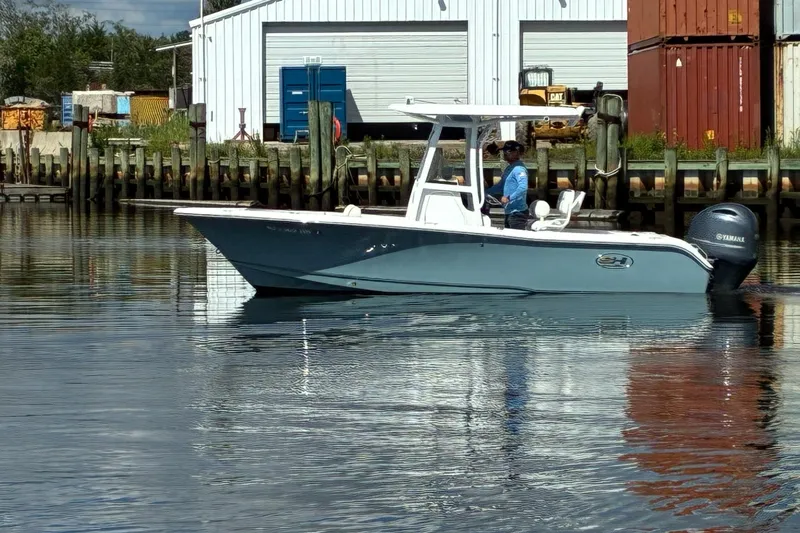 Slide: The Image of 2020 Sea Hunt Triton 210 boat on calm water near a dock, with a person onboard. - 2
