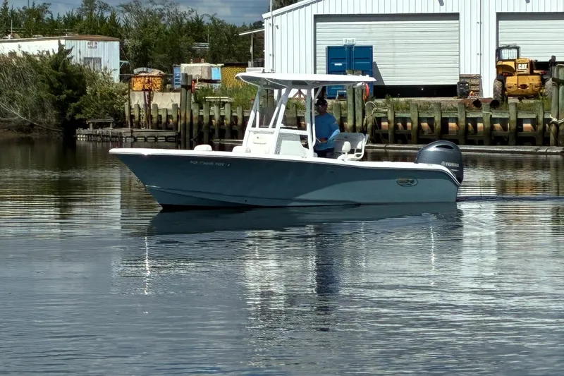 Slide: The Image of 2020 Sea Hunt Triton 210 boat on calm water near industrial dock. - 3