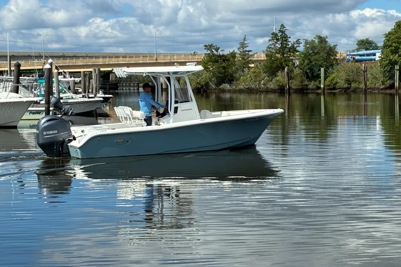 Slide: The Image of 2020 Sea Hunt Triton 210 boat cruising on calm water near a marina. - 4