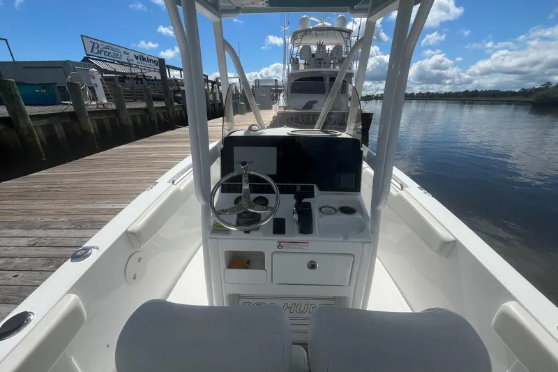 Slide: The Image of 2020 Sea Hunt Triton 210 boat docked, featuring steering console and clear blue sky. - 5