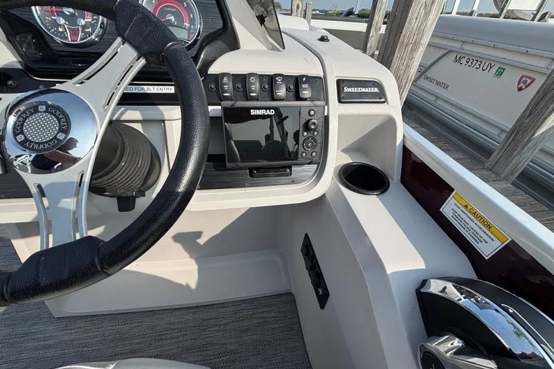 Slide: The Image of 2024 Godfrey Sw2286SB boat dashboard with steering wheel, Simrad display, and control panel. - 6