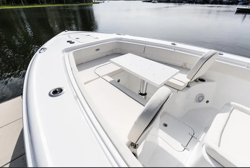 Slide: The Image of 2025 Sea Hunt Ultra 275 SE boat interior with seating and table on calm water. - 14