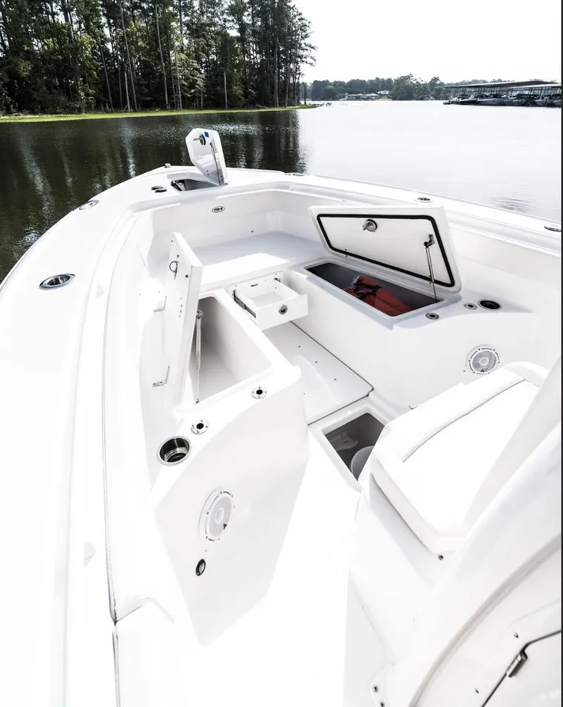 Slide: The Image of 2025 Sea Hunt Ultra 275 SE boat interior with open storage compartments on a calm lake. - 19