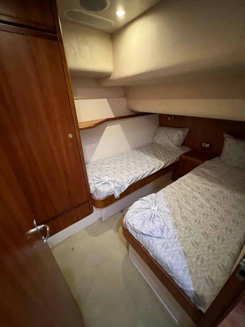 Slide: The Image of 2009 Bertram Convertible cabin with twin beds and wooden interior. - 19
