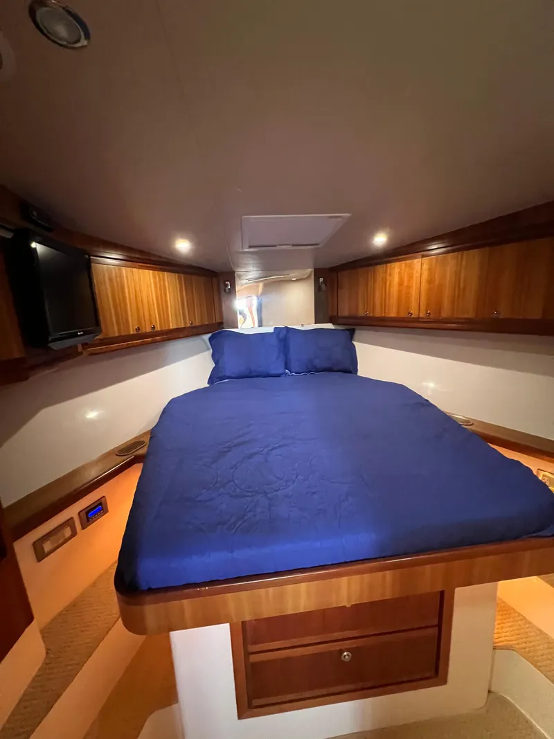 Slide: The Image of 2009 Bertram Convertible cabin interior with blue bedding and wooden cabinetry. - 20