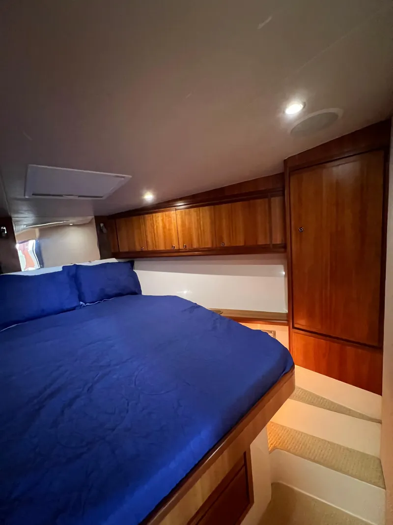 Slide: The Image of 2009 Bertram Convertible cabin with blue bedding and wooden cabinetry. - 21