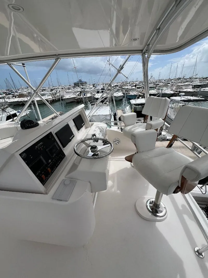 Slide: The Image of 2009 Bertram Convertible yacht helm with white seating, overlooking marina. - 6