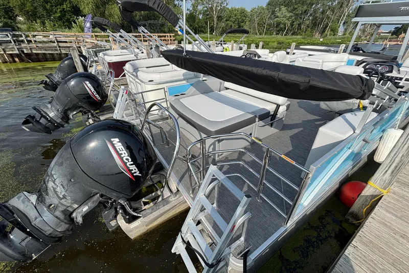Slide: The Image of 2024 Godfrey SW2286SFL pontoon boat with Mercury outboard engines docked at marina. - 2