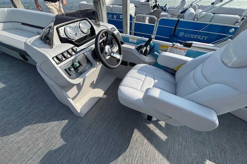 Slide: The Image of 2024 Godfrey SW2286SFL boat interior with steering console and plush seating. - 5