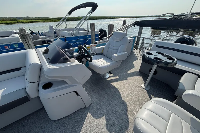 Slide: The Image of 2024 Godfrey SW2286SFL pontoon boat interior with helm, seating, and cup holders. - 7
