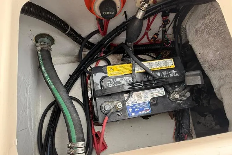 Slide: The Image of Battery compartment of a 2005 Grady-White Escape 209 boat with wiring and hoses. - 13