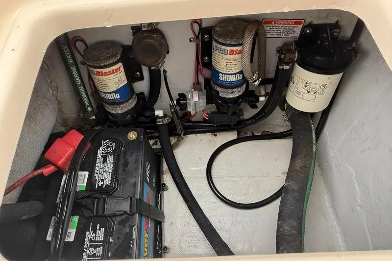 Slide: The Image of 2005 Grady-White Escape 209 boat battery and pump compartment with wiring and components. - 14