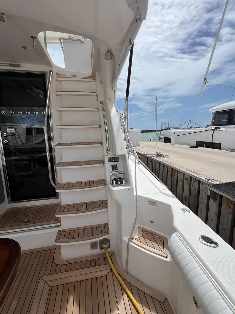 Slide: The Image of 2016 Riviera 45 OPEN yacht with wooden deck and staircase, docked at marina. - 2