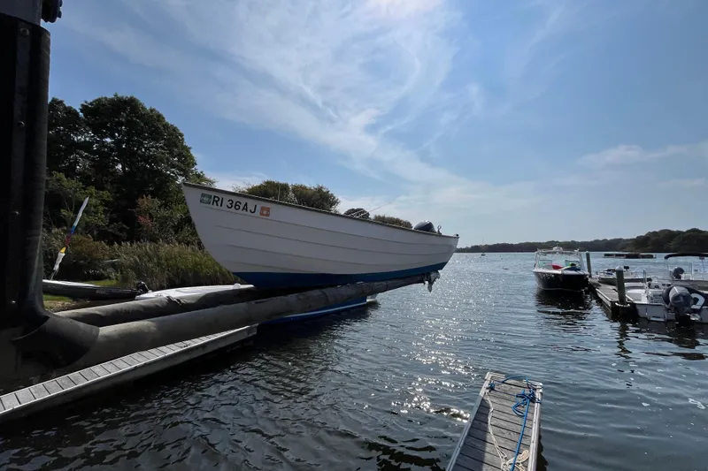 Slide: The Image of 1986 Stur-Dee 16 Dory boat on a lift by a serene lake. - 11