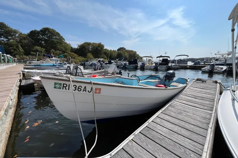 Slide: The Image of 1986 Stur-Dee 16 Dory boat docked at a marina on a sunny day. - 2