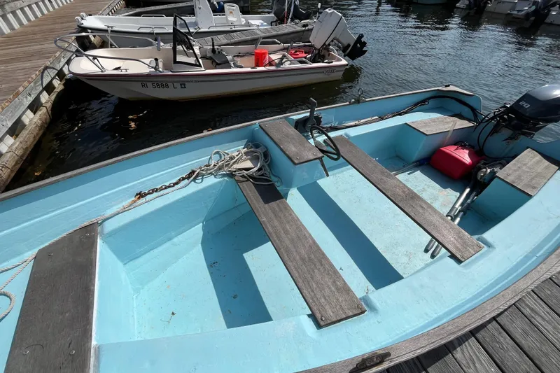Slide: The Image of 1986 Stur-Dee 16 Dory boat docked, featuring blue interior and wooden seats. - 3