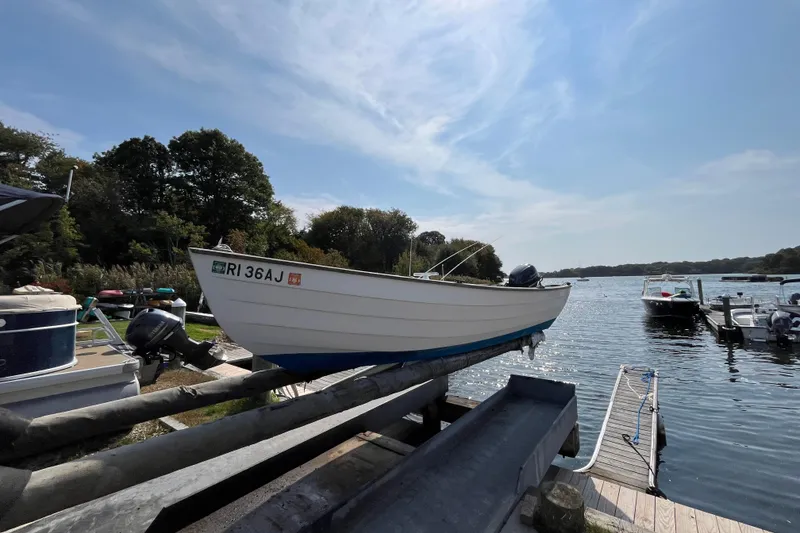 Slide: The Image of 1986 Stur-Dee 16 Dory boat on dock, scenic lake view, clear sky. - 8