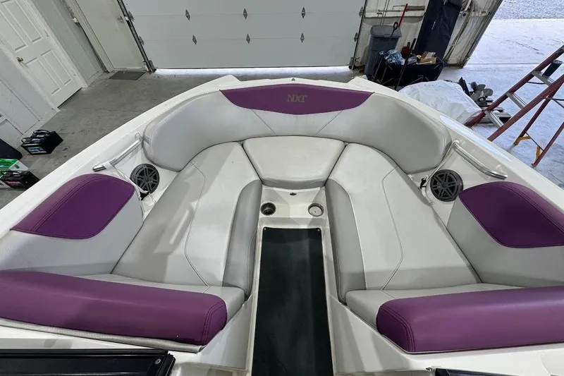 Slide: The Image of 2016 MasterCraft NXT22 boat interior with purple and white seating in a garage. - 13