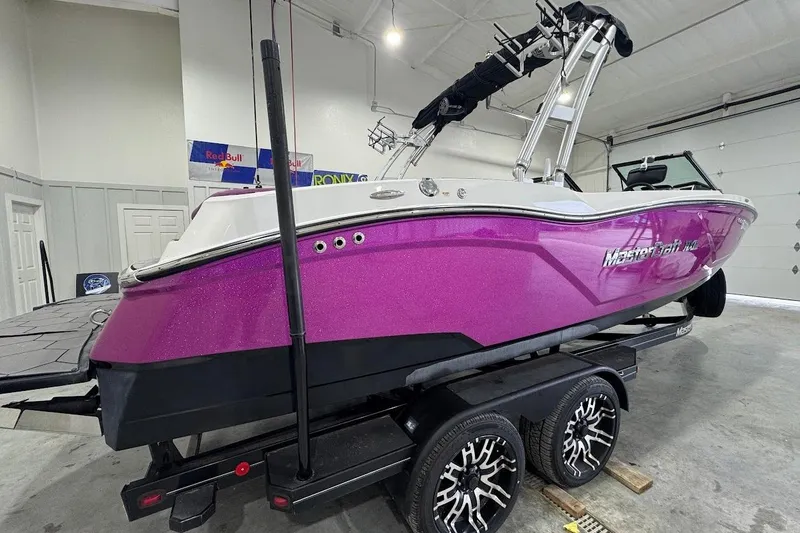 Slide: The Image of 2016 MasterCraft NXT22 boat with vibrant purple hull on a trailer in a garage. - 5