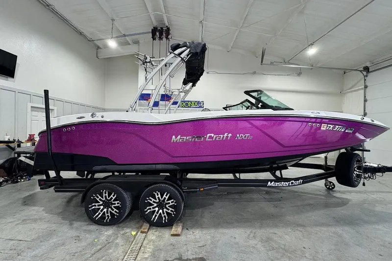 Slide: The Image of 2016 MasterCraft NXT22 boat in vibrant purple, displayed indoors on a trailer. - 6