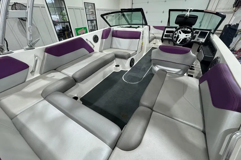Slide: The Image of 2016 MasterCraft NXT22 boat interior with purple and gray seating, modern dashboard, and spacious layout. - 7