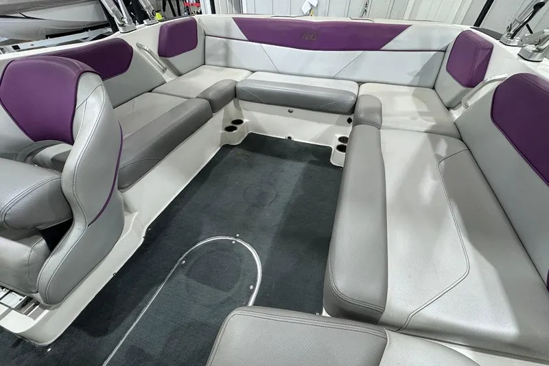 Slide: The Image of 2016 MasterCraft NXT22 boat interior with gray and purple seating, spacious layout. - 9