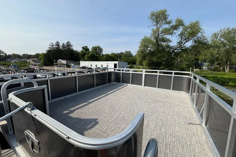 Slide: The Image of 2023 TAHOE AVALON Cascade pontoon boat deck with railing, surrounded by trees and buildings. - 13