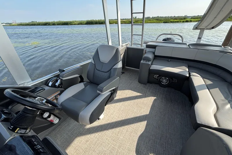 Slide: The Image of 2023 TAHOE AVALON Cascade boat interior with steering wheel and seating, on a calm lake. - 5