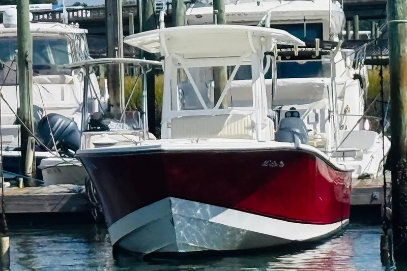 Slide: The Image of 2003 Regulator 26 Center Console boat docked in marina, featuring a sleek red hull. - 2