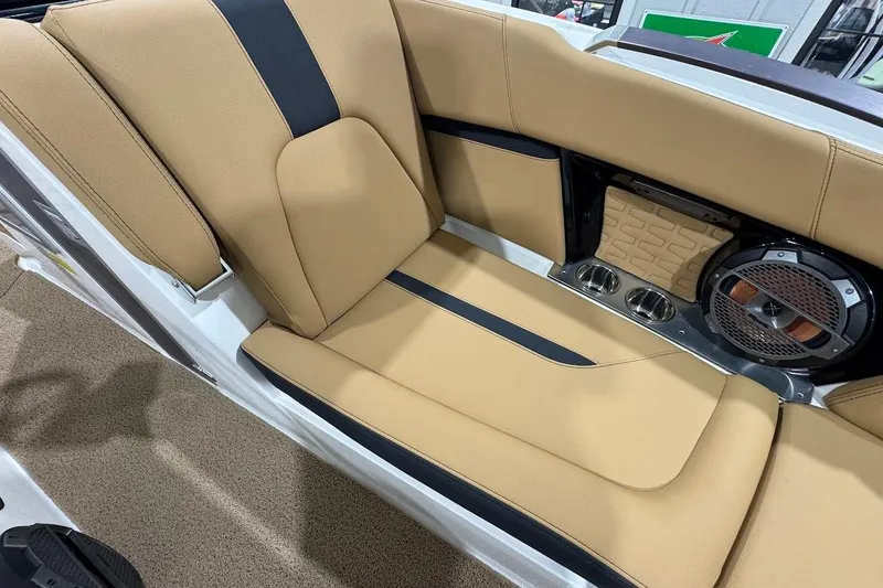 Slide: The Image of 2021 MasterCraft X24 boat interior with tan and black seating, speaker, and cup holders. - 16