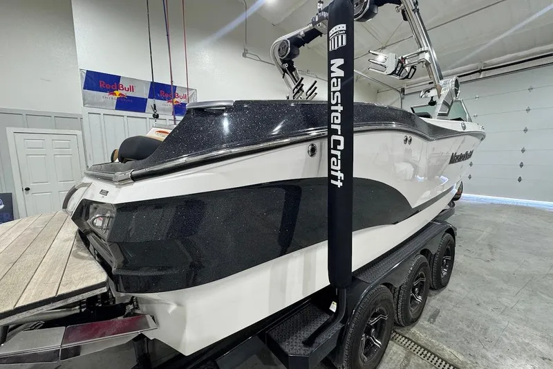 Slide: The Image of 2021 MasterCraft X24 boat in garage, black and white design, on trailer. - 5