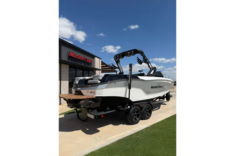 Slide: The Image of 2023 MasterCraft XT24 boat on trailer outside dealership under blue sky. - 3