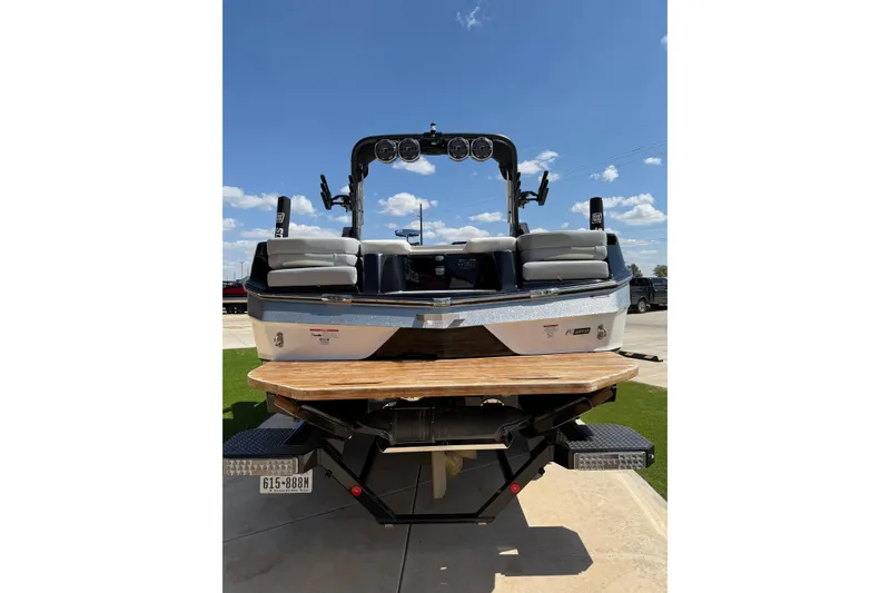 Slide: The Image of 2023 MasterCraft XT24 boat rear view with seating and tower against blue sky. - 5