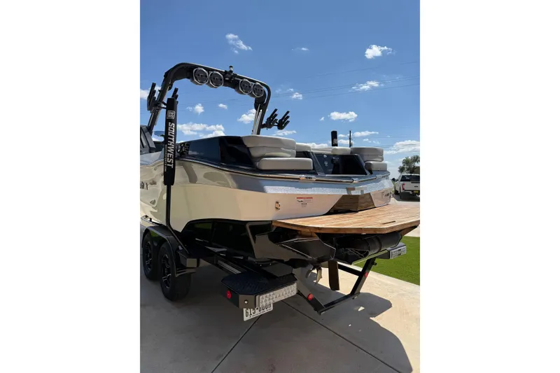 Slide: The Image of 2023 MasterCraft XT24 boat on trailer under clear blue sky. - 6