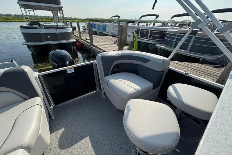 Slide: The Image of Pontoon boat interior with gray seating, docked at a marina. Godfrey SW2286MT, 2025 model. - 12