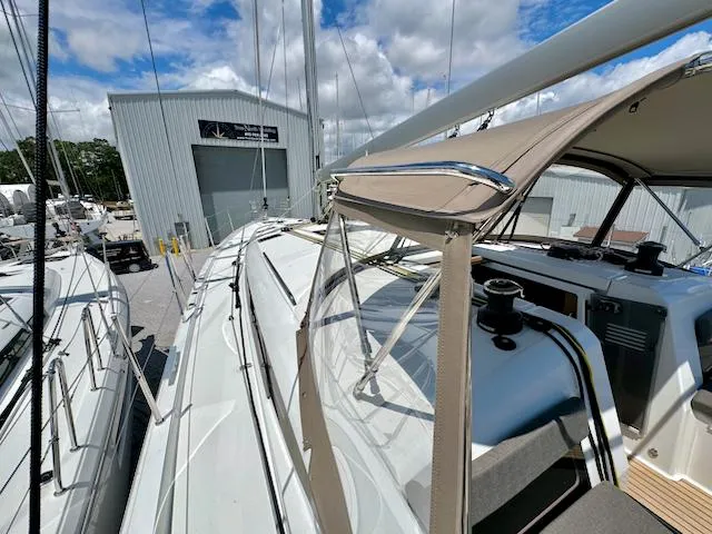 Slide: The Image of 2023 Jeanneau Sun Odyssey 490 sailboat docked near a marina building under a cloudy sky. - 12