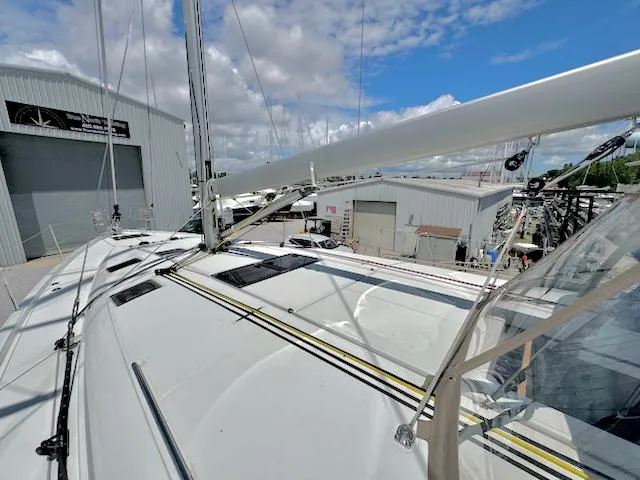 Slide: The Image of 2023 Jeanneau Sun Odyssey 490 sailboat docked near marina buildings under a blue sky. - 13