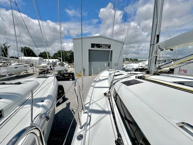 Slide: The Image of 2023 Jeanneau Sun Odyssey 490 sailboats docked at a marina under a cloudy sky. - 14