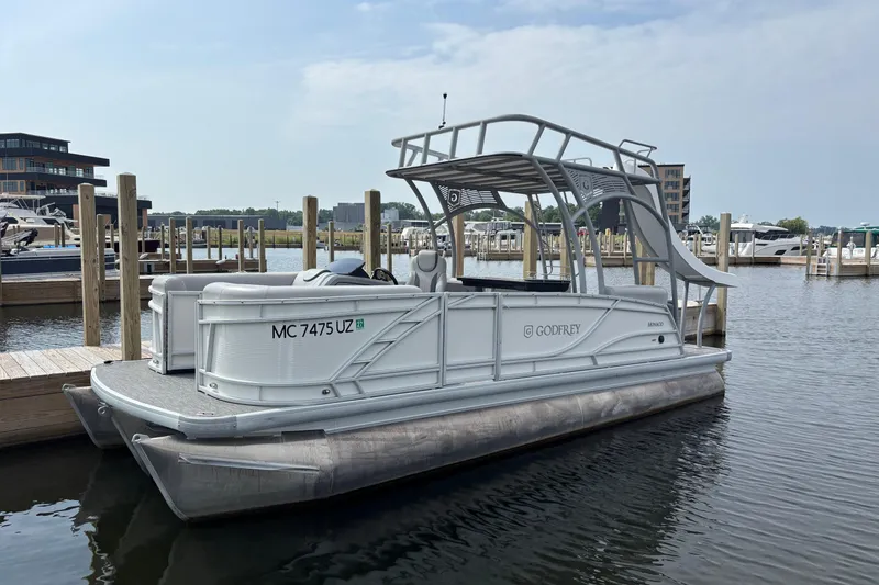 Slide: The Image of 2025 Godfrey MC235SDB pontoon boat docked at marina, featuring sleek design and modern amenities. - 0