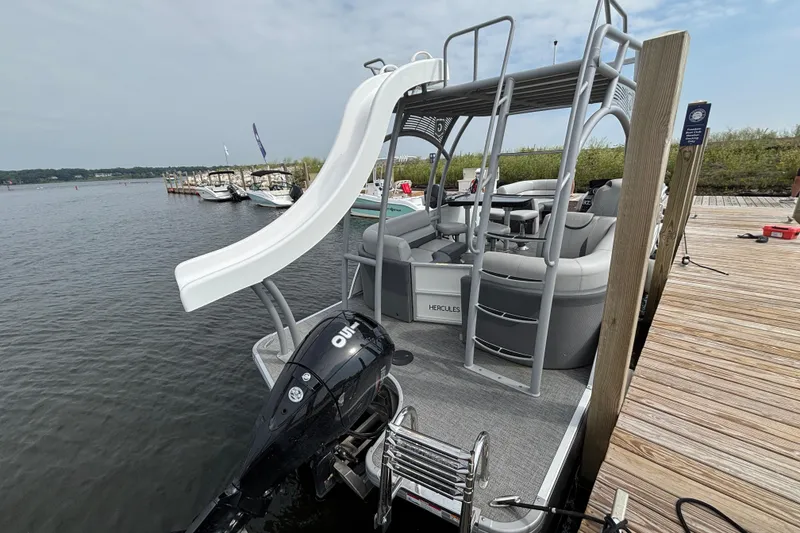 Slide: The Image of 2025 Godfrey MC235SDB pontoon boat with slide, docked by a wooden pier. - 3