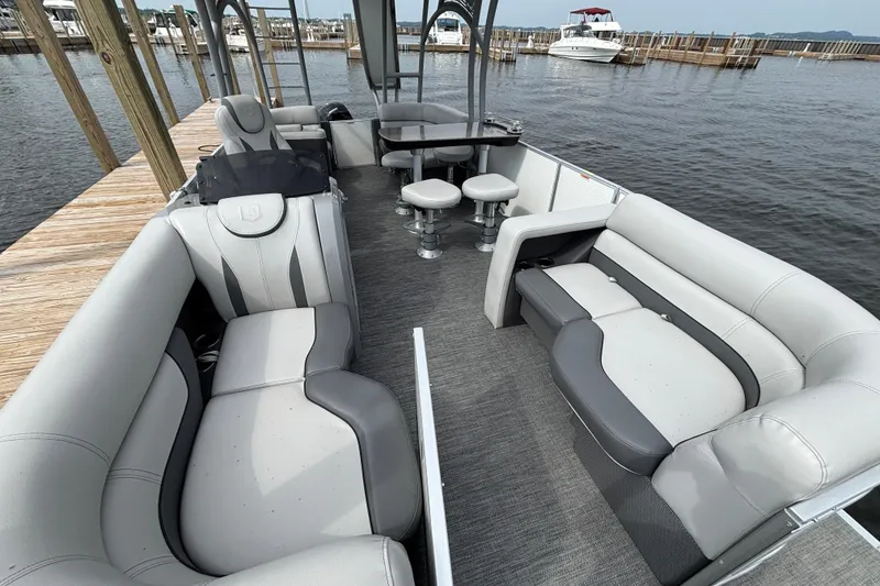 Slide: The Image of 2025 Godfrey MC235SDB pontoon boat interior with gray seating, docked by the water. - 4