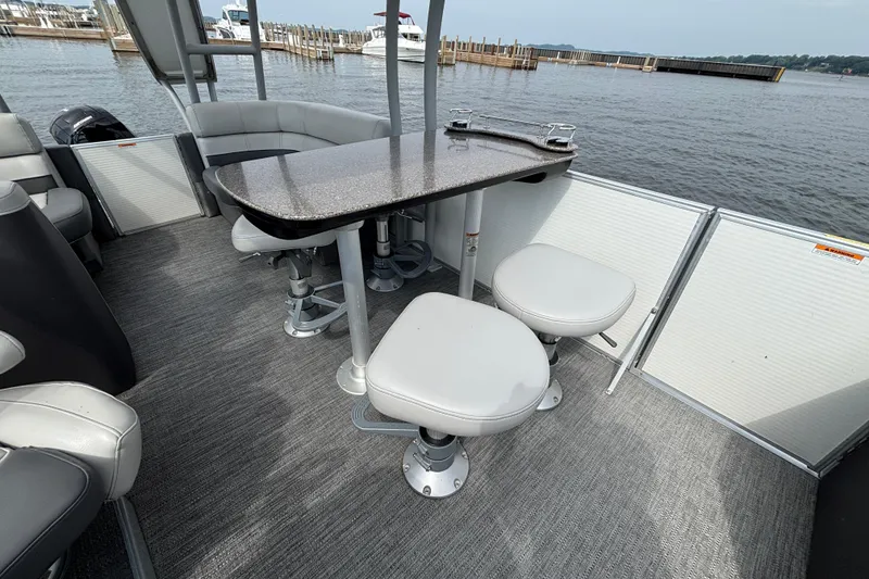 Slide: The Image of Luxurious 2025 Godfrey MC235SDB pontoon boat interior with seating and table, docked by the water. - 5