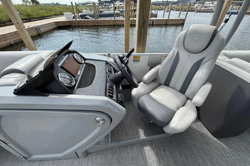 Slide: The Image of 2025 Godfrey MC235SDB boat cockpit with modern steering and comfortable seating at a marina. - 7