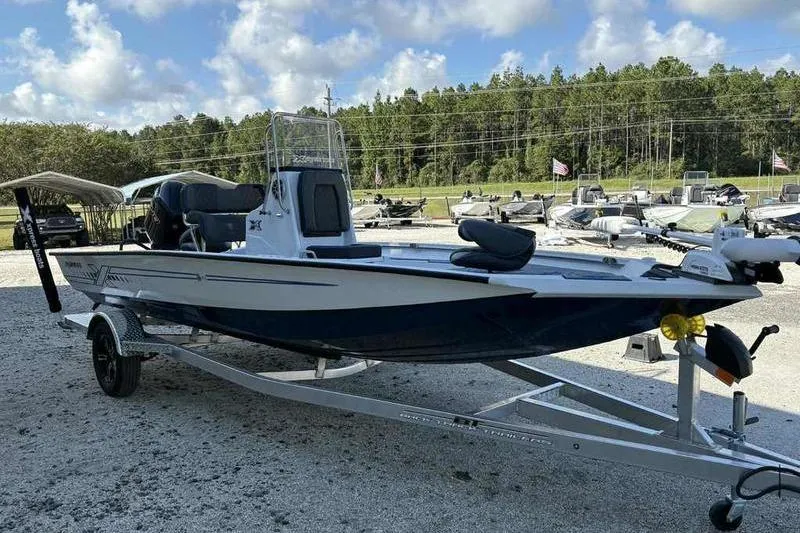 Slide: The Image of 2026 Xpress H20B Bay boat on trailer, parked outdoors under a clear sky. - 13