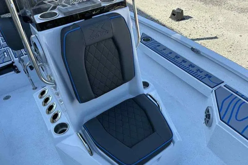 Slide: The Image of 2026 Xpress H20B Bay boat seat with black and blue accents, featuring rod holders and measuring scale. - 4