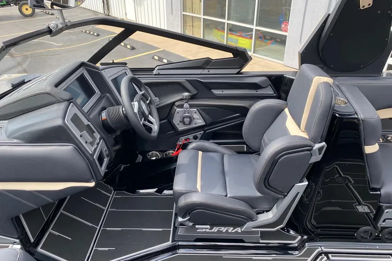 Slide: The Image of 2023 Supra SE450 boat interior with sleek black and beige seating and modern dashboard. - 13