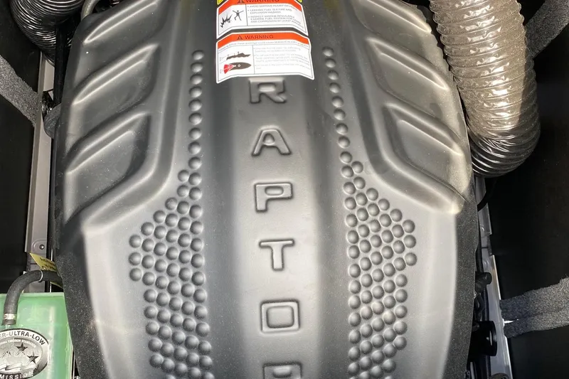 Slide: The Image of 2023 Supra SE450 engine cover with textured design and warning labels. - 15