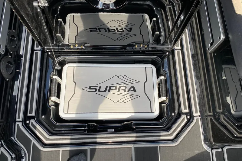 Slide: The Image of 2023 Supra SE450 boat storage compartment with branded lid and sleek design. - 17