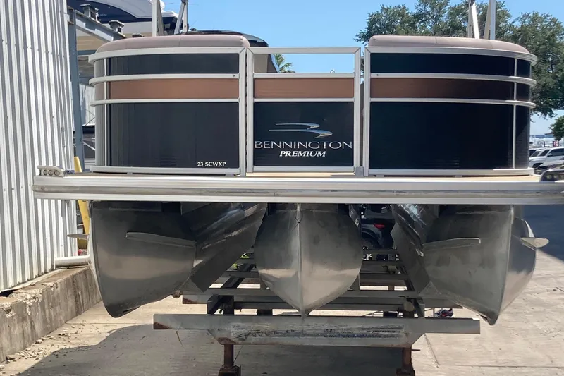 Slide: The Image of 2018 Bennington 23 SX pontoon boat docked, featuring spacious seating and canopy. - 1
